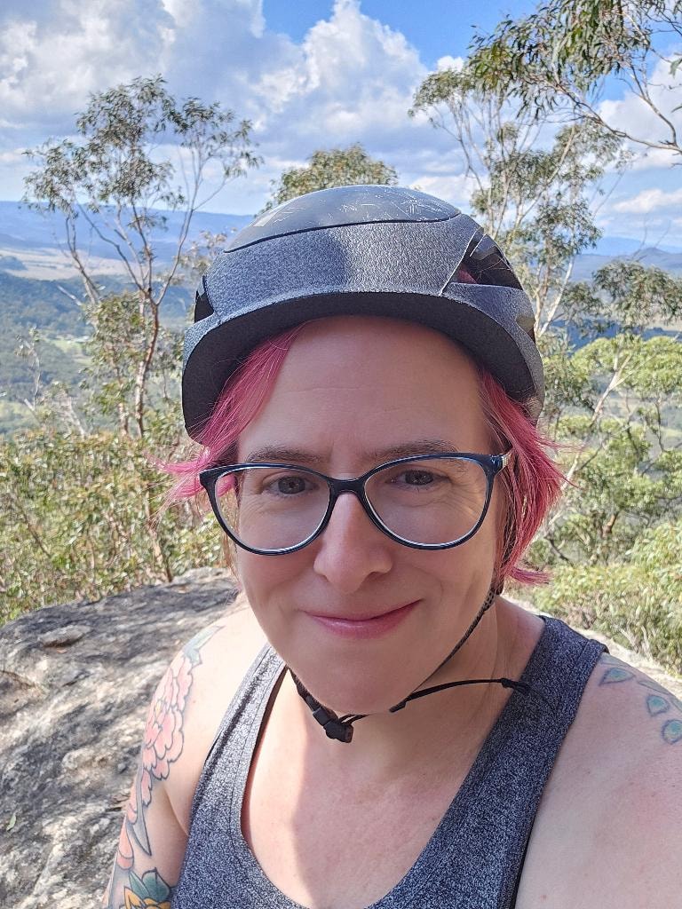 Dr Mara Hickey at a hilltop lookout wearing a bike helmet